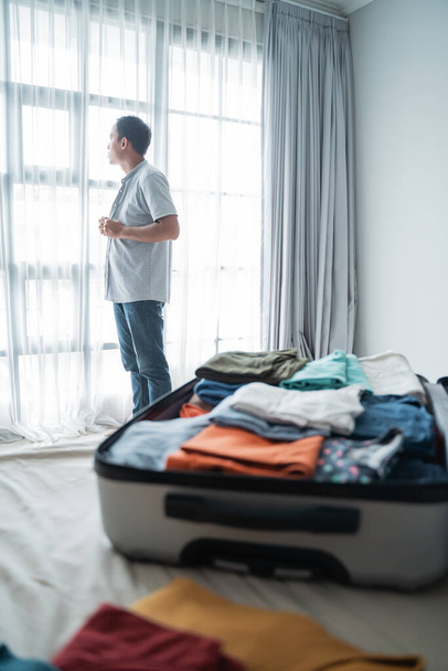 young man wearing clothes after opening his suitcase in the bedroom - Foto, immagini