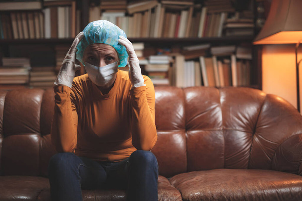 Žena s ochrannou antivirovou maskou sedí doma v izolaci / karanténě. - Fotografie, Obrázek