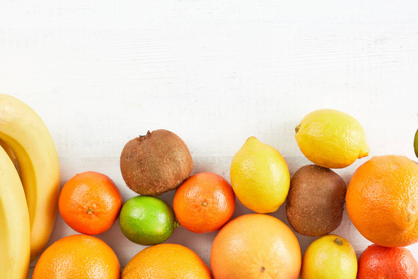 Assortment of tropical fruits orange, tangerine, banana, grapefruit, lemon, lime, kiwi on white background. Fresh fruit set. Copy space. - Fotó, kép