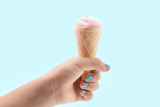 Ice cream candy in the hand on the blue background - Фото, изображение