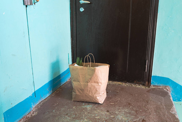 Delivery during quarantine. Self-isolation. Social Services. A paper bag with goods and food in front of the door, the concept of neighborhood Quarantine assistance due to coronavirus infection Covid 19 - Photo, Image