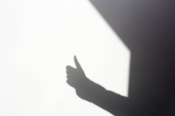 силует тіні рука робить тумби вгору на білій стіні, ізольовані вдома
 - Фото, зображення