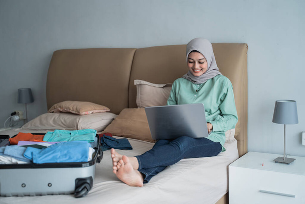 asian muslim woman using laptop to looking departure schedules via online application - Foto, afbeelding