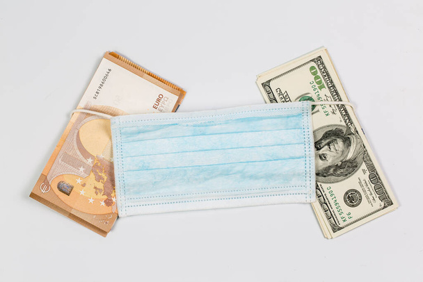 Medizinische Maske gegen Virusinfektion während einer Pandemie und Quarantäne mit viel Geld als Zeichen der Gesundheitskosten. - Foto, Bild