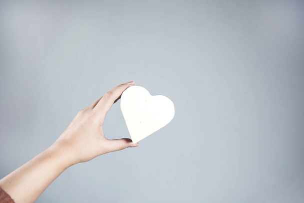 woman hand holding heart on gray background - Foto, Imagen