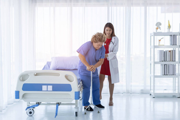 Joven atractivo médico asiático está ayudando a un viejo paciente caminando, hospital y concepto de salud
. - Foto, imagen