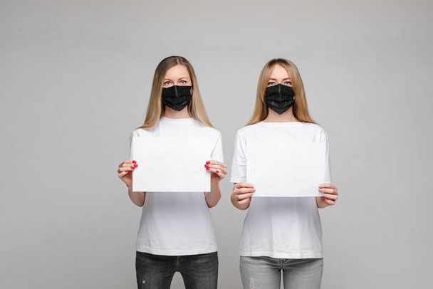 Dos mujeres con máscaras y pancartas. Detener virus concepto
. - Foto, Imagen