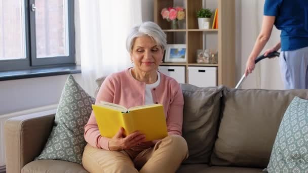 old woman reading book and housekeeper at home - Video