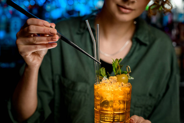 Nahaufnahme. Frau mit Pinzette dekoriert Cocktail sanft mit Glasstäben - Foto, Bild