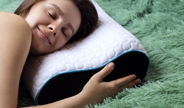 Молодая женщина лежит на кровати с ортопедической подушкой
 - Фото, изображение