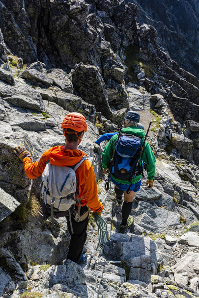 Tatranska Polianka, Slovaquie - 01 septembre 2019 : Guide de montagne descendant la corde dans le terrain rocheux de ses clients (touristes) qui descendent du pic Gerlach dans les Tatras
. - Photo, image