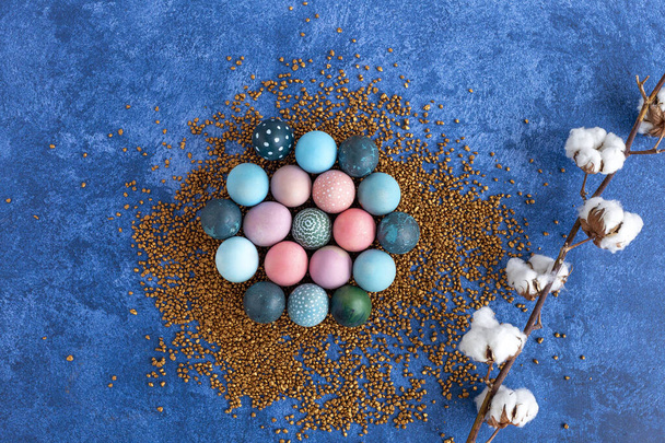 Színes húsvéti tojások arany díszes köveken. Sötétkék háttér. Ünnepi dekorációk, húsvéti koncepció háttér. - Fotó, kép