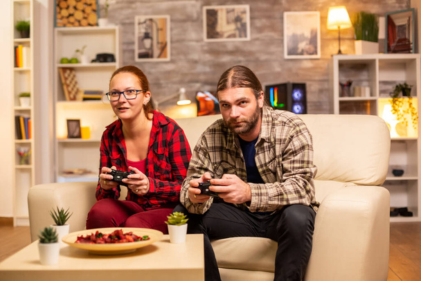 Pareja de jugadores jugando videojuegos en el televisor con controladores inalámbricos en las manos
 - Foto, Imagen