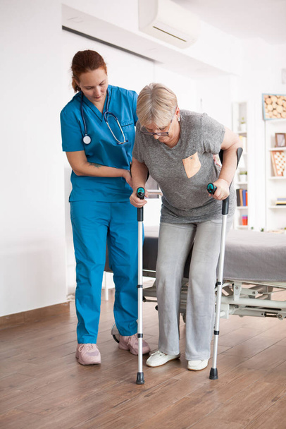 Old woman in nursing home walking with crutches - Фото, зображення