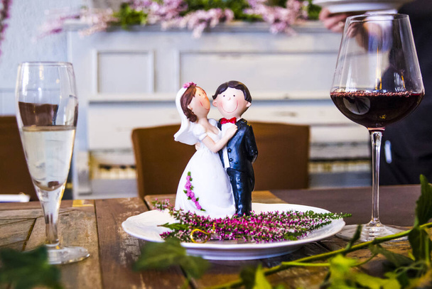 νύφη και γαμπρός για την υπέροχη γαμήλια τούρτα, μικρά ειδώλια, με ένα ποτήρι κρασί και ένα ποτήρι αφρώδες κρασί - Φωτογραφία, εικόνα