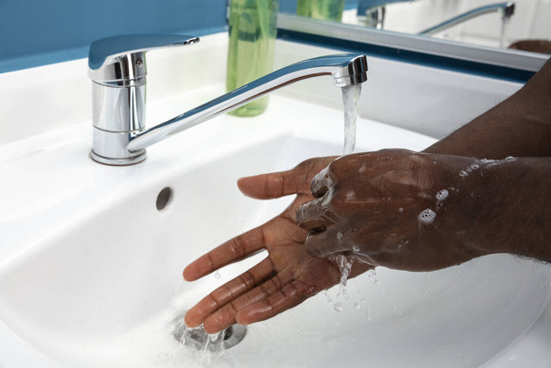 Man washing hands carefully in bathroom close up. Prevention of infection and pneumonia virus spreading - Fotoğraf, Görsel