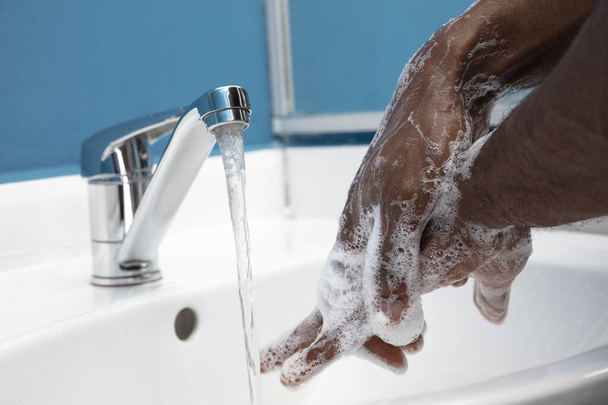 Man washing hands carefully in bathroom close up. Prevention of infection and pneumonia virus spreading - 写真・画像