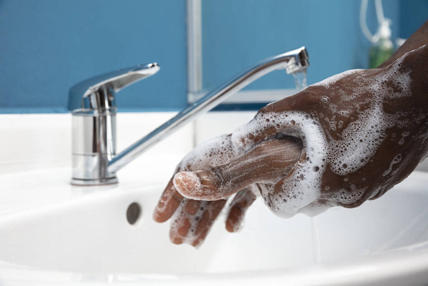 Uomo che si lava le mani con attenzione in bagno da vicino. Prevenzione dell'infezione e diffusione del virus della polmonite
 - Foto, immagini