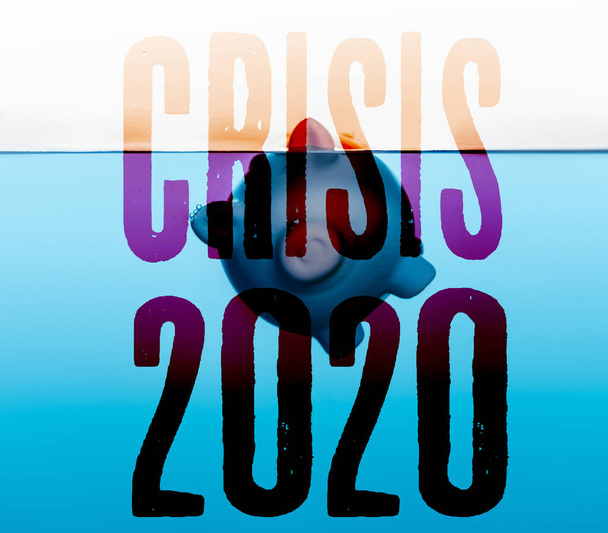 piggy bank going under blue water isolated on white, coronavirus 2020 crisis concept - Photo, Image
