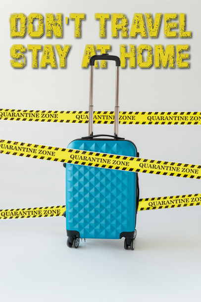 μπλε βαλίτσα σε κίτρινο και μαύρο κίνδυνο προειδοποιητική ταινία ασφαλείας σε λευκό, δεν ταξιδεύουν, μείνετε στο σπίτι εικονογράφηση - Φωτογραφία, εικόνα