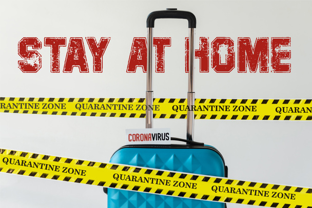 maleta azul con tarjeta coronavirus en cinta de seguridad de advertencia de peligro amarillo y negro aislada en blanco con ilustración de estancia en casa
 - Foto, Imagen