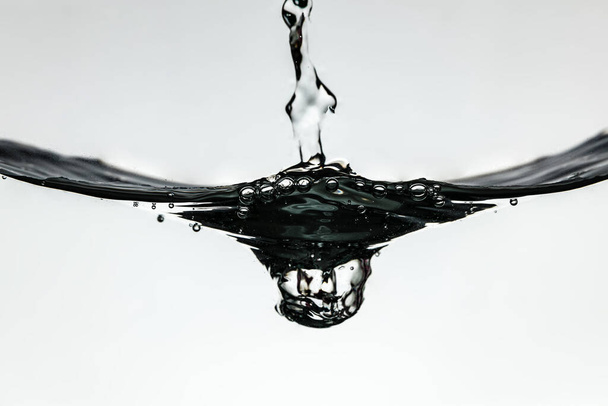Öntővíz fröccsenés a víz felszínén fehér alapon, elszigetelt - Fotó, kép