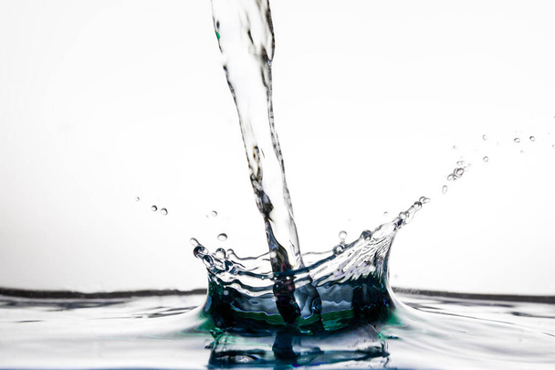 Pouring water splash on water surface on white background, isolated - Photo, Image
