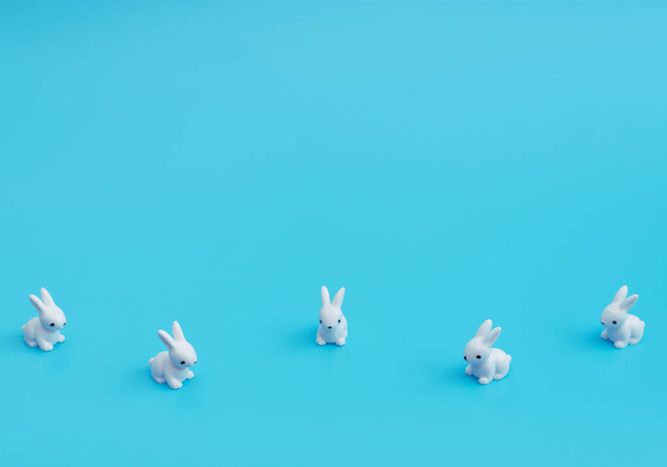 A lot of small white rabbits on blue background. Happy Easter holiday concept. Greeting card. Concept of minimalism. Copy space for your text.  - Photo, Image