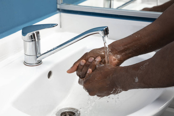 Man washing hands carefully in bathroom close up. Prevention of infection and pneumonia virus spreading - 写真・画像