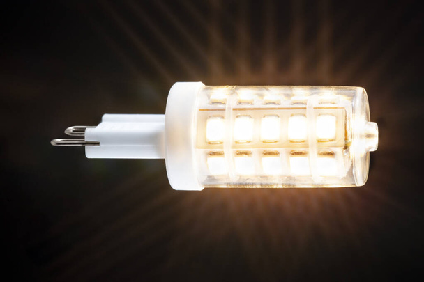 Gloeiende energiebesparende G9 ledlamp met een donkere achtergrond - Foto, afbeelding