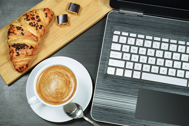Coffee, croissant and laptop on the table. Breakfast - Φωτογραφία, εικόνα