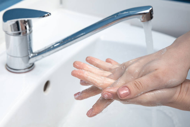 Donna che si lava le mani con attenzione in bagno da vicino. Prevenzione dell'infezione e diffusione del virus della polmonite
 - Foto, immagini