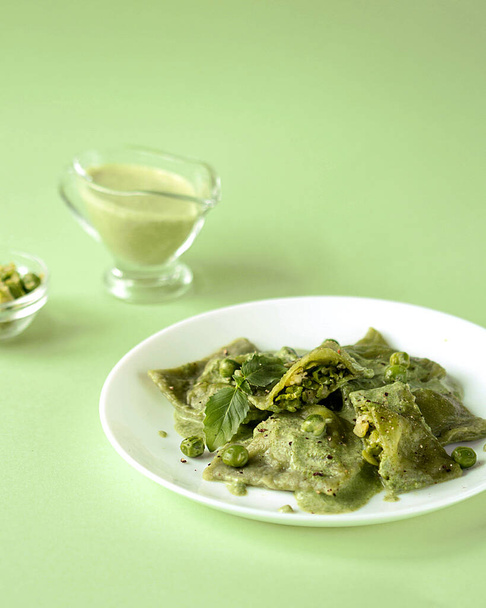 Green spinach ravioli with green pea filling on a green background. - Фото, изображение