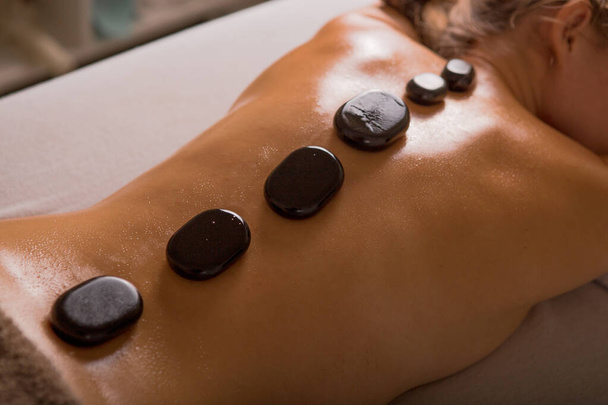 Visão superior da mulher madura relaxante durante a massagem de pedra quente
 - Foto, Imagem