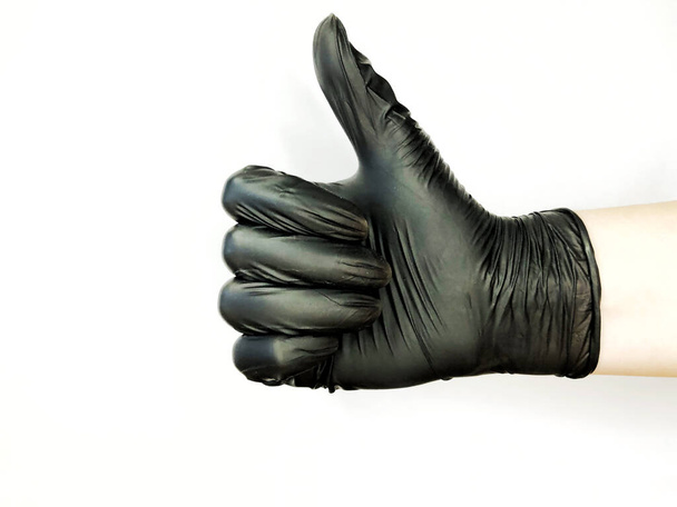 Hand in zwarte handschoen geïsoleerd op wit met duim omhoog. - Foto, afbeelding