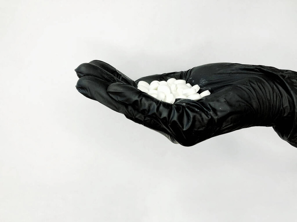 guante negro con pastillas sobre un fondo blanco
 - Foto, Imagen