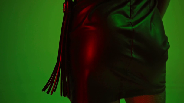 σαγηνευτική γυναίκα κρατώντας μαστίγιο στο πράσινο  - Πλάνα, βίντεο