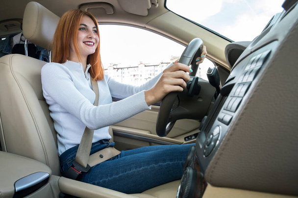 Giovane donna rossa alla guida di una macchina sorridente felicemente
. - Foto, immagini