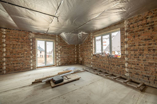 Interior de la casa de ladrillo sin terminar con piso de hormigón y paredes desnudas listo para el enlucido en construcción. Desarrollo inmobiliario - Foto, imagen