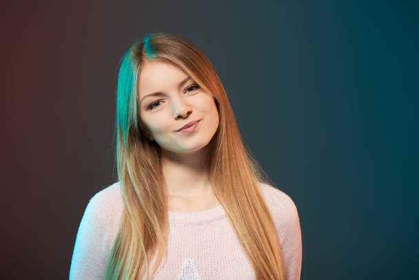 Young smiling female with colorful backlight, closeup studio portrait - 写真・画像