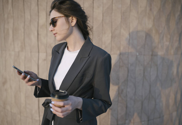 Close-up business womans hands hold lactose-free coffee and phone. Business woman at lunch solves work issues using the phone - Φωτογραφία, εικόνα