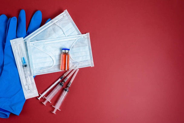 vacina coronavírus, seringas e máscara sobre fundo vermelho, vista superior. espaço de cópia. o conceito de uma pandemia, gripe, ficar em casa
 - Foto, Imagem