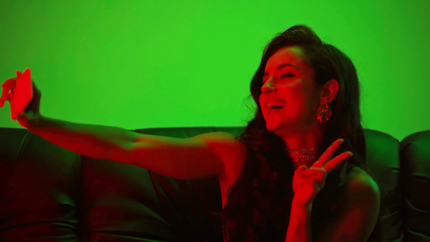 sexy Frau schickt Luftkuss und macht Selfie auf Grün - Filmmaterial, Video