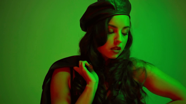 sexy dziewczyna w beret i kurtka stojąc na zielony - Materiał filmowy, wideo