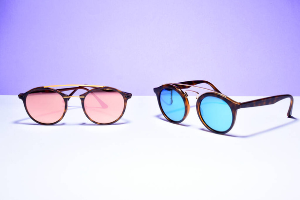 aurinkolasit silmälasit pastelliväripaperin taustalla
  - Valokuva, kuva