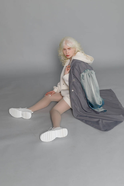 beautiful albino girl with white skin, natural lips and white curly hair wearing stylish white sweater, close up photo, copy space, beauty, fashion. Blonde girl - Valokuva, kuva