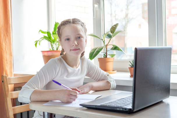Schoolgirl studying at home using laptop. Home school, online education, home education, quarantine concept - Image - Foto, afbeelding