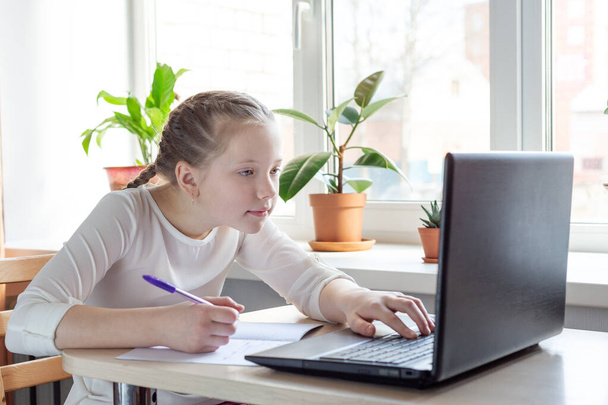 Schoolgirl looks at a laptop screen. Social distance, self- isolation. Home school, online education, home education, quarantine concept - Image - Fotoğraf, Görsel