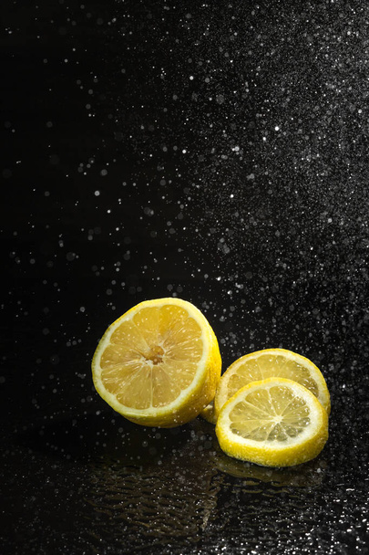 黒の背景にレモンと水のスプレー - 写真・画像