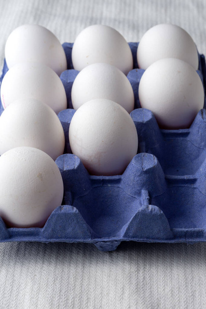 Mavi kartondaki dokuz beyaz yumurtanın üst görünümü, kopyalama alanı ile dikey - Fotoğraf, Görsel